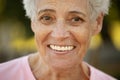 Portrait of smiling elderly woman at park. Close up portrait. Happy thoughful mature woman relaxing outdoor.