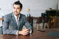 Portrait of smiling elegant business man wearing fashion suit sitting at desk in modern office room, looking at camera. Royalty Free Stock Photo