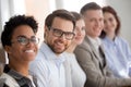 Portrait of smiling employees sit in row looking at camera