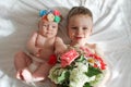 Portrait of smiling Europeans blond boy with blue eyes and girl on a white background with a bouquet of flowers.