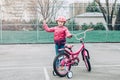 Smiling excited Caucasian preschooler girl standing with pink bicycle in helmet on court field outside on spring day showing champ Royalty Free Stock Photo