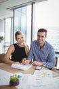 Portrait of smiling executives discussing over paper at desk Royalty Free Stock Photo