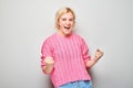 Portrait of smiling face blond young woman clenching fists and rejoicing, celebrating victory isolated on white studio background Royalty Free Stock Photo