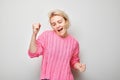 Portrait of smiling face blond young woman clenching fists and rejoicing, celebrating victory isolated on white studio background Royalty Free Stock Photo