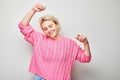 Portrait of smiling face blond young woman clenching fists and rejoicing, celebrating victory  on white studio background Royalty Free Stock Photo