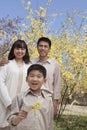 Portrait of smiling family and little boy holding a yellow flower blossom in the park in springtime Royalty Free Stock Photo