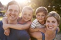 Portrait Of Smiling Family Outdoors In Summer Park Against Flaring Sun