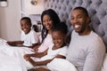 Portrait of smiling family sitting together on bed Royalty Free Stock Photo