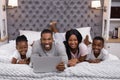 Portrait of smiling family using laptop while lying together on bed Royalty Free Stock Photo
