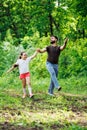 Portrait of smiling family walking pacing in forest around trees, having fun. Little girl holding hand of happy father. Royalty Free Stock Photo