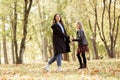 Portrait of smiling family of young woman mother and teenage girl daughter walking among trees in forest park in autumn. Royalty Free Stock Photo