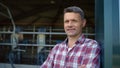 Portrait smiling farmer dairy facility. Happy man resting observing livestock Royalty Free Stock Photo