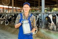 Smiling farmer standing in cowshed at dairy farm with milk churn Royalty Free Stock Photo