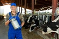 Smiling farmer standing in cowshed at dairy farm with milk churn Royalty Free Stock Photo