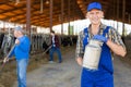 Smiling farmer standing in cowshed at dairy farm with milk churn Royalty Free Stock Photo