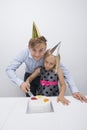 Portrait of smiling father cutting birthday cake with daughter at table