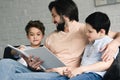 portrait of smiling father and sons reading book together Royalty Free Stock Photo