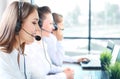 Portrait of smiling female customer service agent wearing headset with colleagues working in background at office. Royalty Free Stock Photo