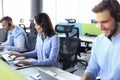 Portrait of smiling female customer service agent wearing headset with colleagues working in background at office Royalty Free Stock Photo