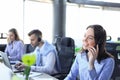 Portrait of smiling female customer service agent wearing headset with colleagues working in background at office Royalty Free Stock Photo