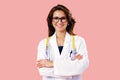 Portrait of smiling female doctor in glasses with arms crossed on pink studio background Royalty Free Stock Photo