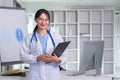 Portrait of a smiling female doctor holding a clipboard Wear a medical coat and stethoscope in a hospital office Royalty Free Stock Photo