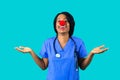 Portrait of a smiling female doctor or nurse wearing blue scrubs uniform and red nose with arms out Royalty Free Stock Photo