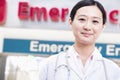 Portrait of smiling female doctor outside of the hospital, emergency room sign in the background Royalty Free Stock Photo