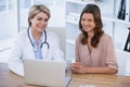 Portrait of smiling female doctor and patient sitting at desk Royalty Free Stock Photo