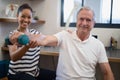 Portrait of smiling female doctor with senior male patient holding dumbbell Royalty Free Stock Photo
