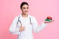 Portrait of smiling female doctor with stethoscope holding measuring tape and apple isolated. Royalty Free Stock Photo