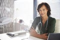 Portrait Of Smiling Female Doctor With Stethoscope Sitting Behind Desk In Office Royalty Free Stock Photo