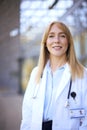 Portrait Of Smiling Female Doctor Wearing White Coat Standing Outside Modern Hospital Building Royalty Free Stock Photo