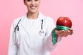 Portrait of smiling female doctor with stethoscope holding measuring tape and apple isolated. Royalty Free Stock Photo