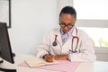 Portrait of smiling female doctor writing in notebook in office Royalty Free Stock Photo