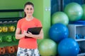 Portrait of smiling female fitness instructor writing in clipboard while standing in gym Royalty Free Stock Photo