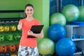 Portrait of smiling female fitness instructor writing in clipboard while standing in gym Royalty Free Stock Photo