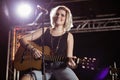 Portrait of smiling female guitarist playing guitar at nightclub Royalty Free Stock Photo