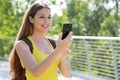 Portrait of smiling female hiker checking GPS coordinates with her smart phone looking for the right direction. Adventure, active