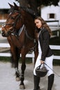 Portrait of smiling female jockey standing by horse near stable Royalty Free Stock Photo