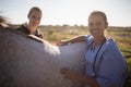 Portrait of smiling female jockey and vet standing by horse Royalty Free Stock Photo