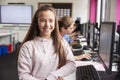 Portrait Of Smiling Female Pupil Sitting In Line Of High School Students Working at Screens In Computer Class