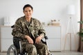 Portrait Of Smiling Female Soldier In Camouflage Uniform Sitting In Wheelchair Indoors Royalty Free Stock Photo