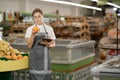 Portrait of smiling female staff in apron using digital tablet while checking fruits in organic section of supermarket. Royalty Free Stock Photo