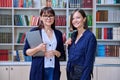Portrait of smiling female teacher and girl student together inside college library Royalty Free Stock Photo