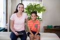 Portrait of smiling female therapist holding digital sitting with arm around boy on bed Royalty Free Stock Photo