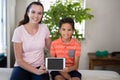 Portrait of smiling female therapist showing digital while sitting with arm around boy on bed Royalty Free Stock Photo