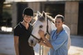 Portrait of smiling female vet with jockey standing by horse