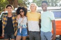 Portrait of smiling friends standing against camper van at campsite