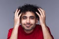 Smiling funny attractive bearded man with dark curly hair, looking in mirror admires his hairstyle. Royalty Free Stock Photo